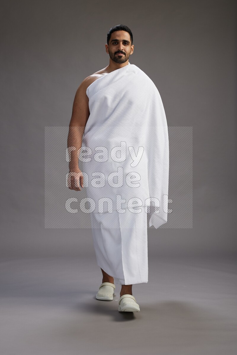 A man wearing Ehram Standing Interacting with the camera on gray background