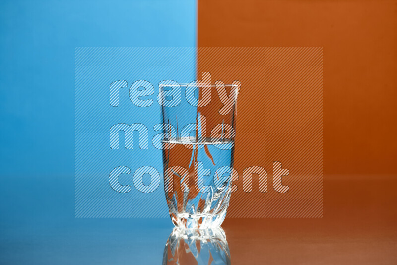 The image features a clear glassware filled with water, set against blue and dark orange background