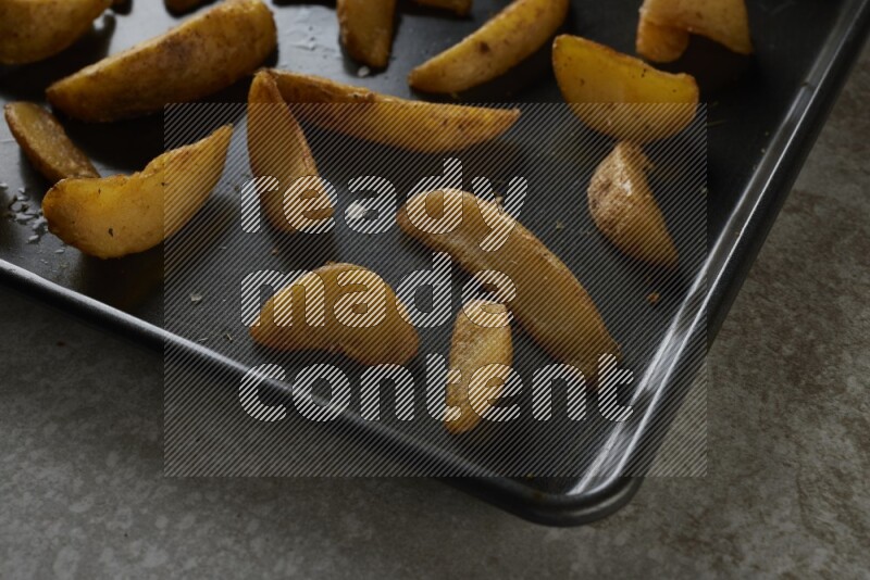 wedges potato in a black stainless steel rectangle tray on grey textured counter top