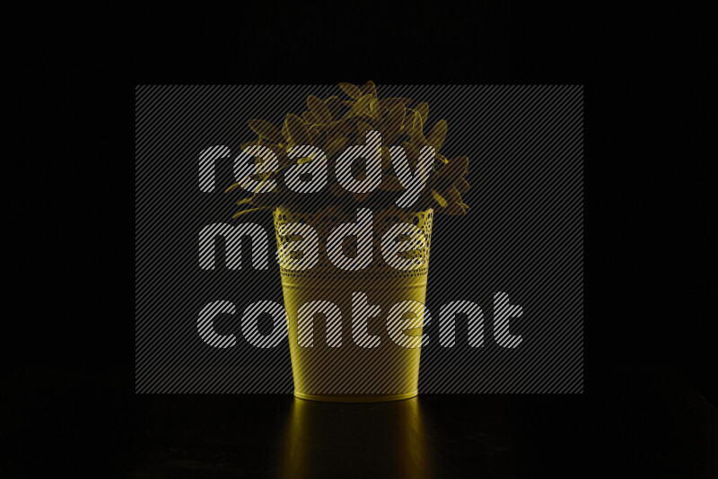 Plastic potted plant with colored rim light against black background