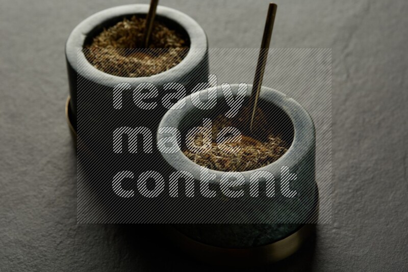 black and white round marble containers filled with herbs on gray textured countertop