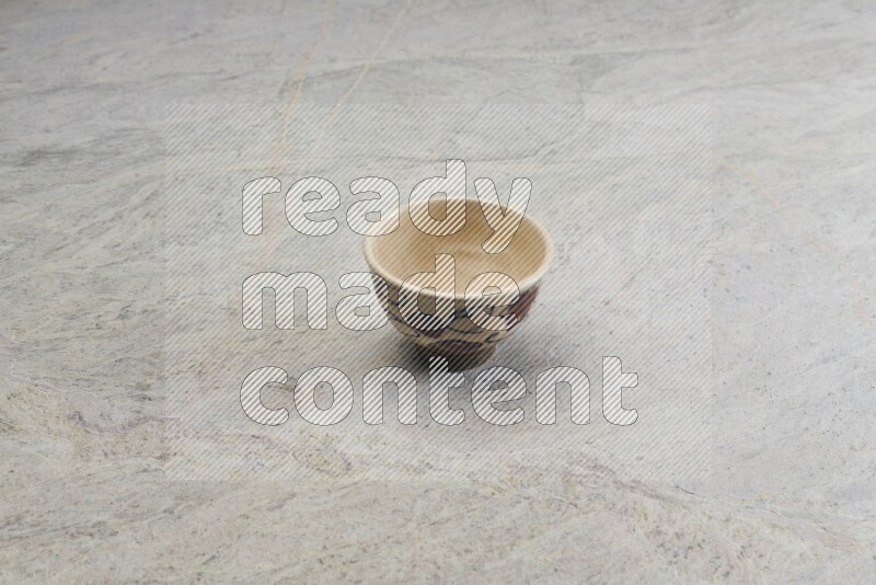 A multicolored pottery bowl on grey marble background