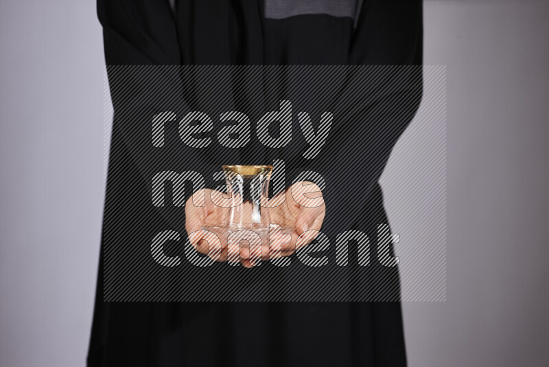 A woman in black abaya holding different glassware in different positions
