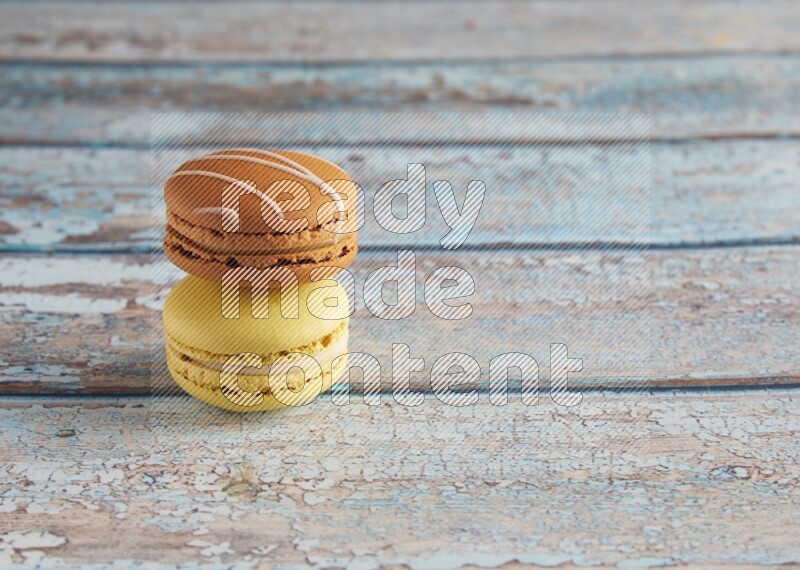45º Shot of of two assorted Brown Irish Cream, and Yellow Lime macarons on light blue background
