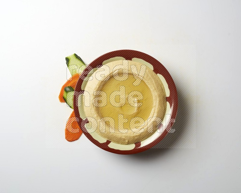 Hummus in a traditional plate garnished with olive oil on a white background