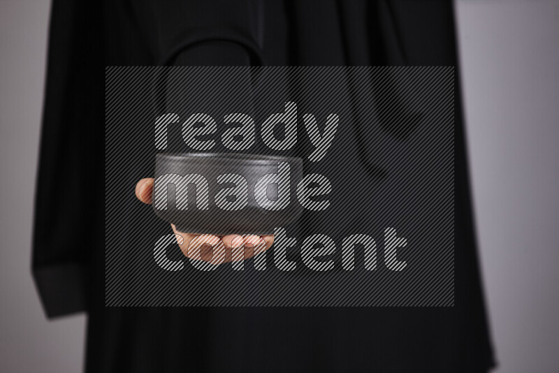 A woman in black abaya holding different pottery essentials in different positions