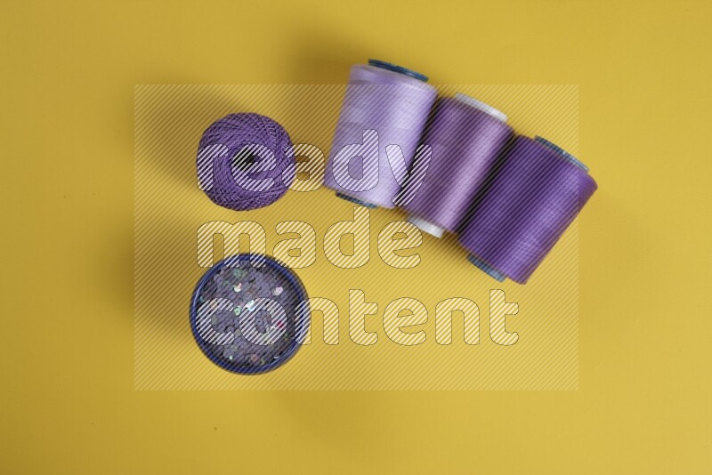 مجموعة من أدوات الخياطة والتفصيل إرجوانية اللون على خلفية صفراء