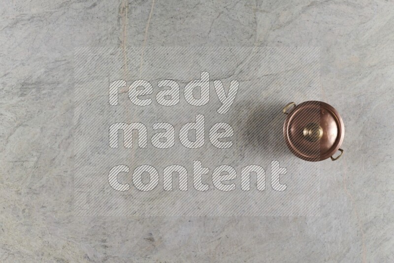 A small copper pot on grey marble background