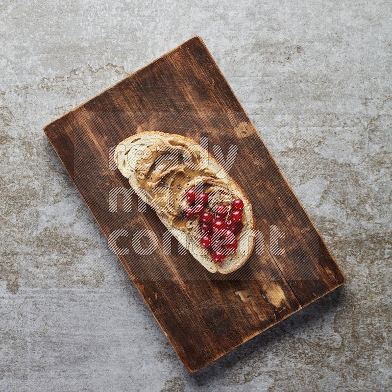 open faced peanut butter sandwich with cranberries and chia seeds grey textured background