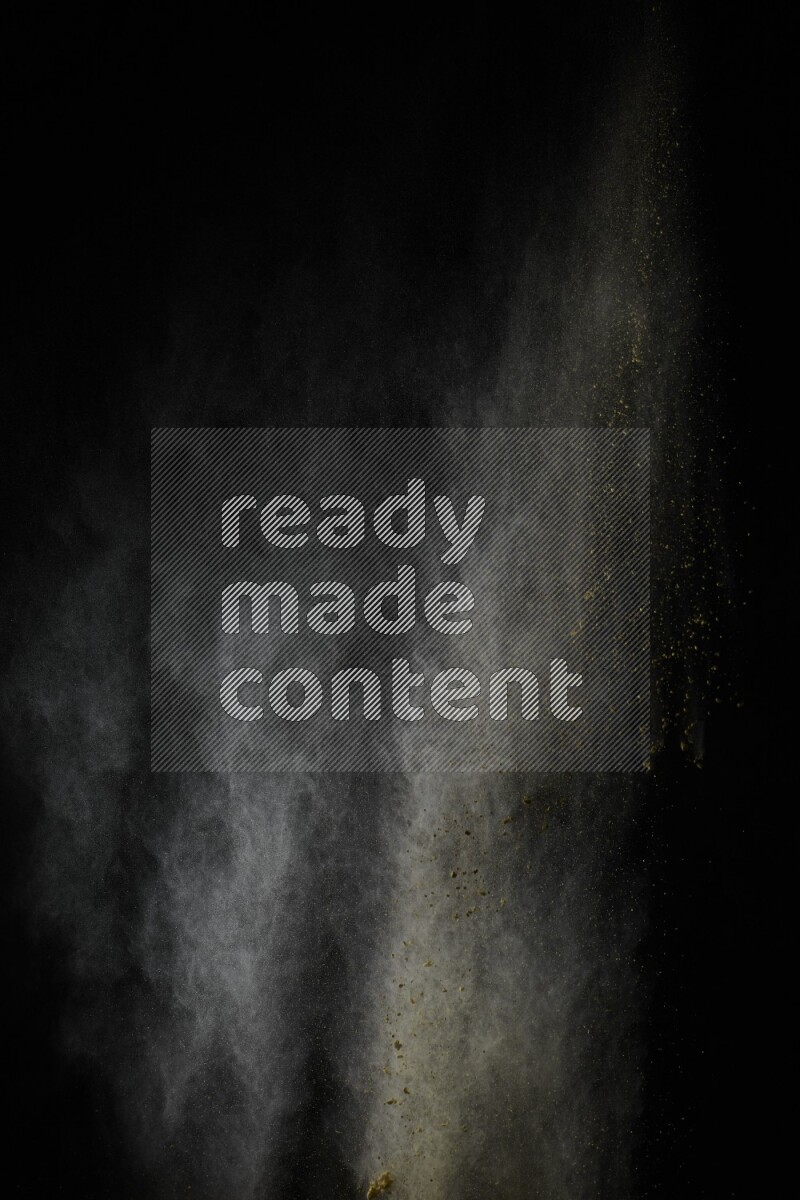 A side view of yellow powder explosion on black background