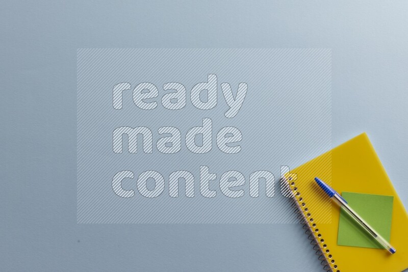 دفتر ملاحظات أصفر مع مستلزمات مدرسية مختلفة على خلفية زرقاء