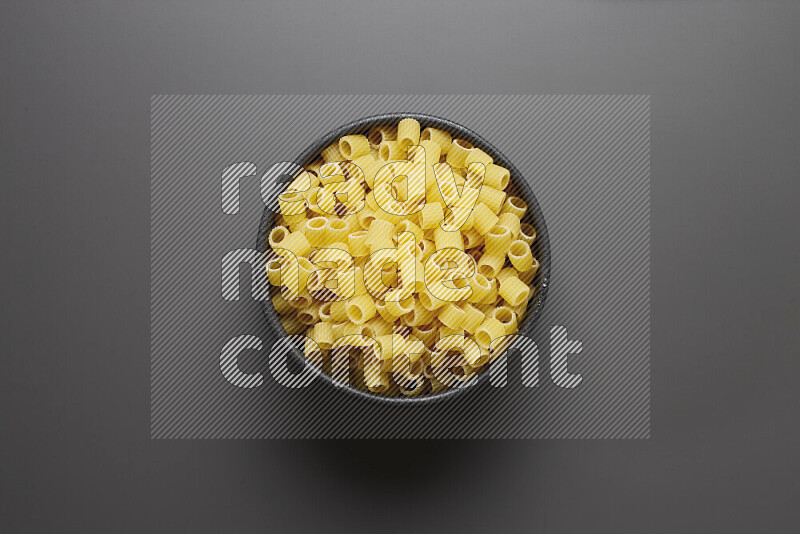Big rings pasta in a pottery bowl on grey background