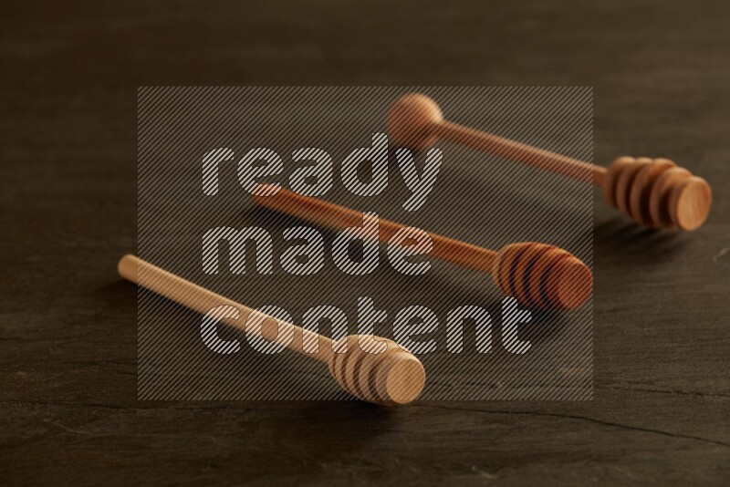 Wooden honey dipper on black slate background