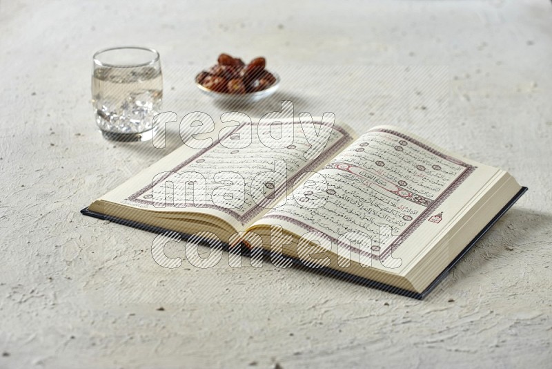 Quran with dates, prayer beads and different drinks on textured white background
