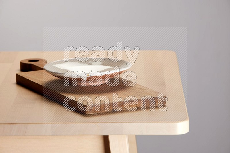 multi-colored pottery Plate placed on a  wooden rectangular cutting board on the edge of wooden table