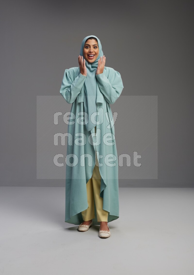 Saudi Woman wearing Abaya standing interacting with the camera on Gray background