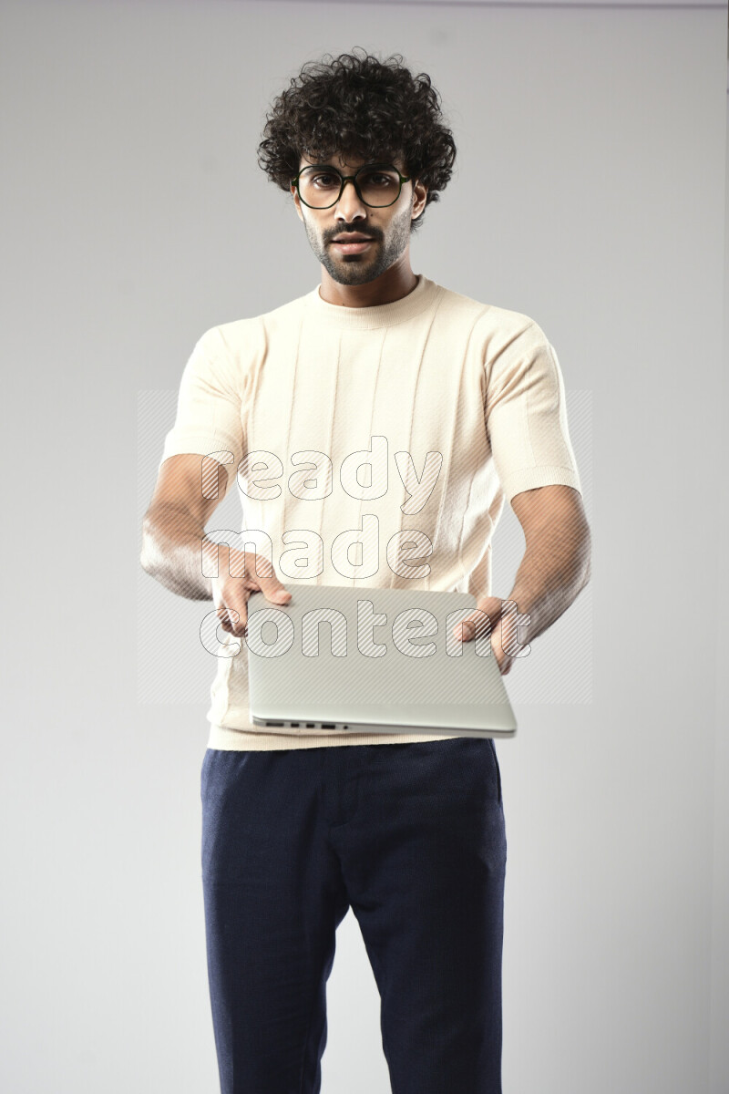 A man wearing casual standing and holding a laptop on white background
