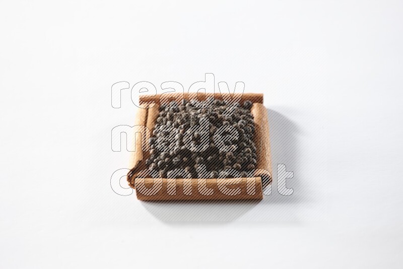 A single square of cinnamon sticks full of black pepper on white flooring