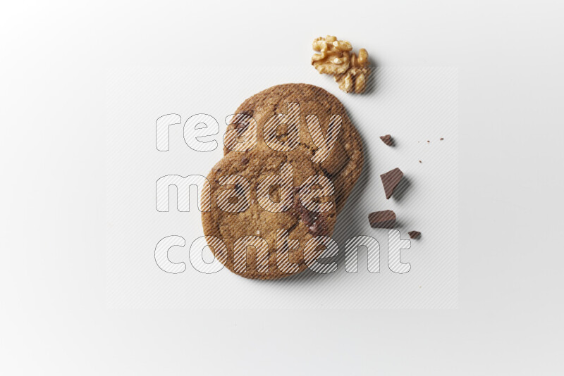 Chocolate chips cookies with chocolate and walnuts beside it on a white background