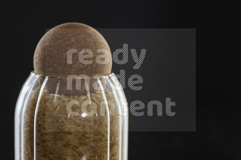 Basmati golden rice in a glass jar on black background