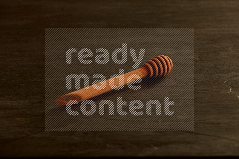 Wooden honey dipper on black slate background