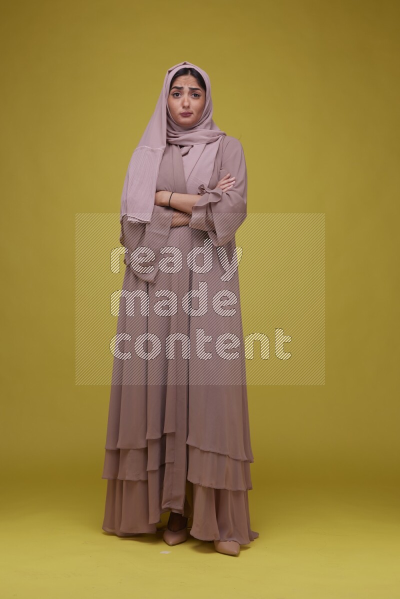 A woman Posing on a Yellow Background wearing Brown Abaya with Hijab