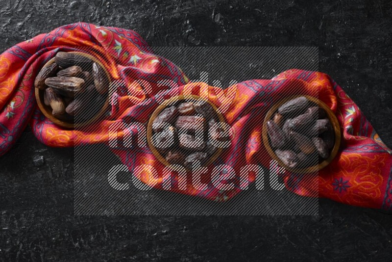 Dates in wooden bowls in a dark setup