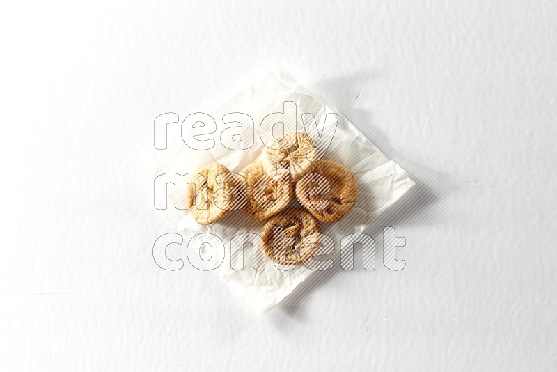 Dried figs on a crumpled piece of paper on a white background in different angles