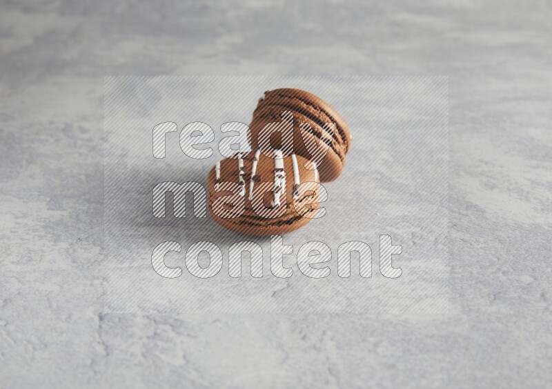45º Shot of two Brown white marbleChocolate Caramel macarons  on white  marble background
