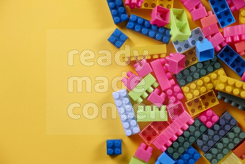 Multicolored plastic building blocks on different backgrounds in top view (kids toys)