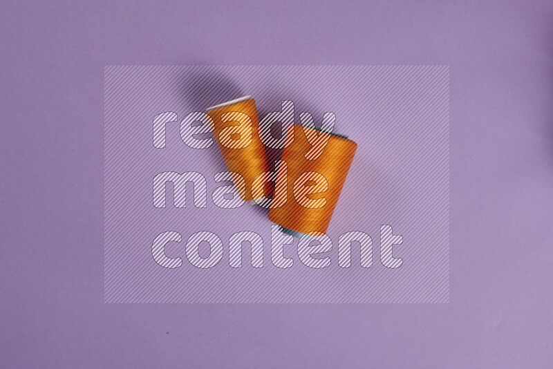 An orange collection of sewing and tailoring tools arranged on a purple background