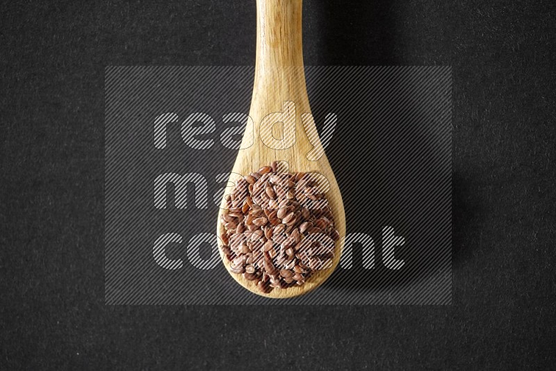 A wooden spoon full of flax on a black flooring in different angles