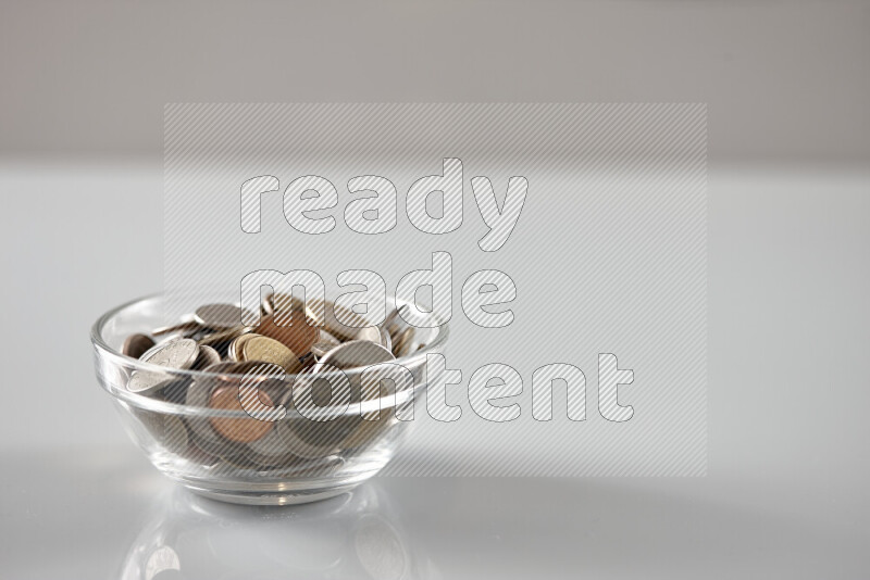 Random old coins in a glass bowl on grey background