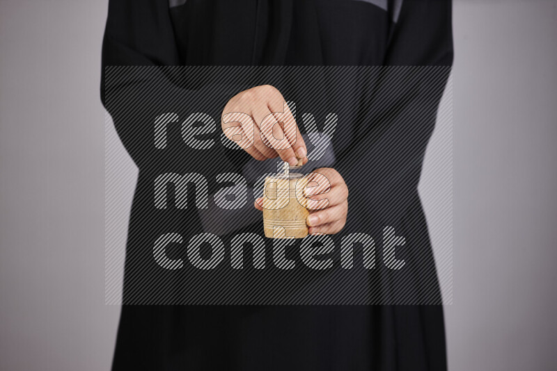 A woman in black abaya holding different wooden essentials in different positions