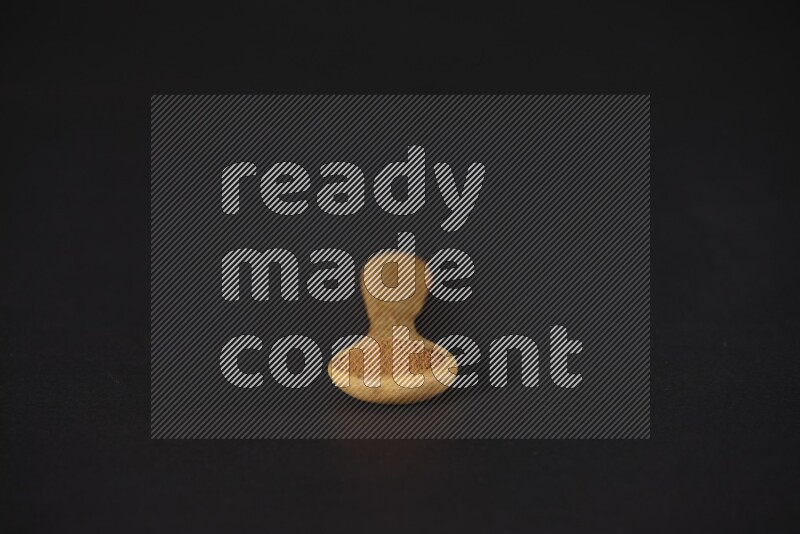 بودرة القرفة في ملعقة خشبية على خلفية سوداء