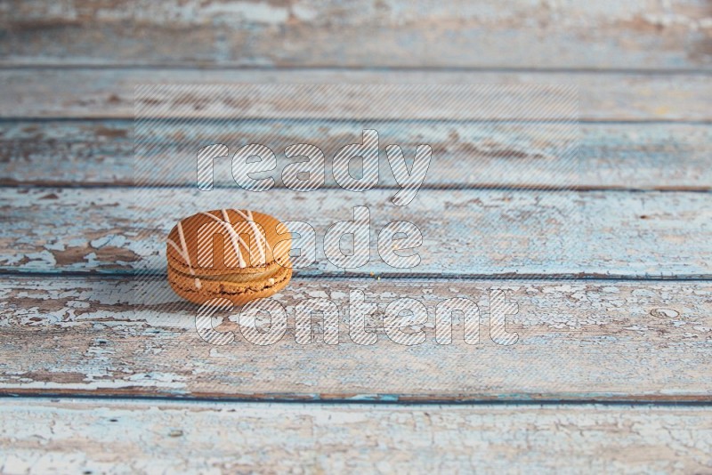 45º Shot of Brown Irish Cream macaron on light blue wooden background