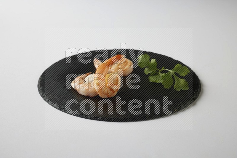 three grilled shrimp  on a black slate direct  on a white back ground