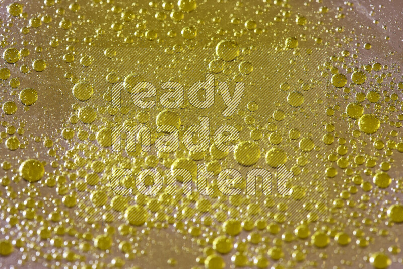 Close-ups of abstract yellow watercolor drops on oil Surface on yellow background