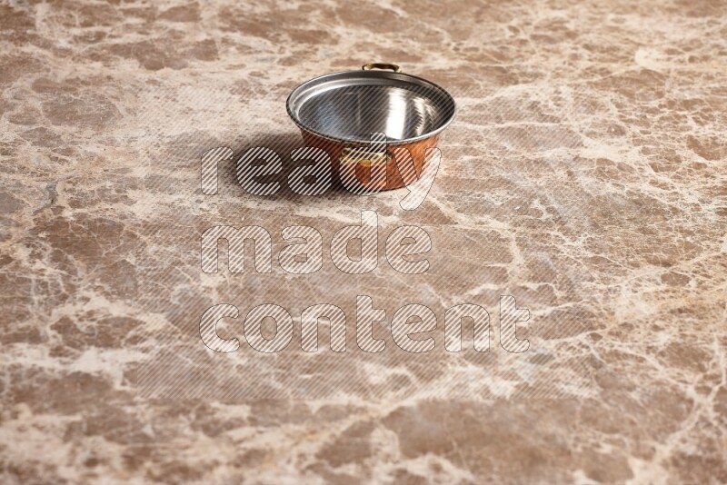 A small copper pot on beige marble background
