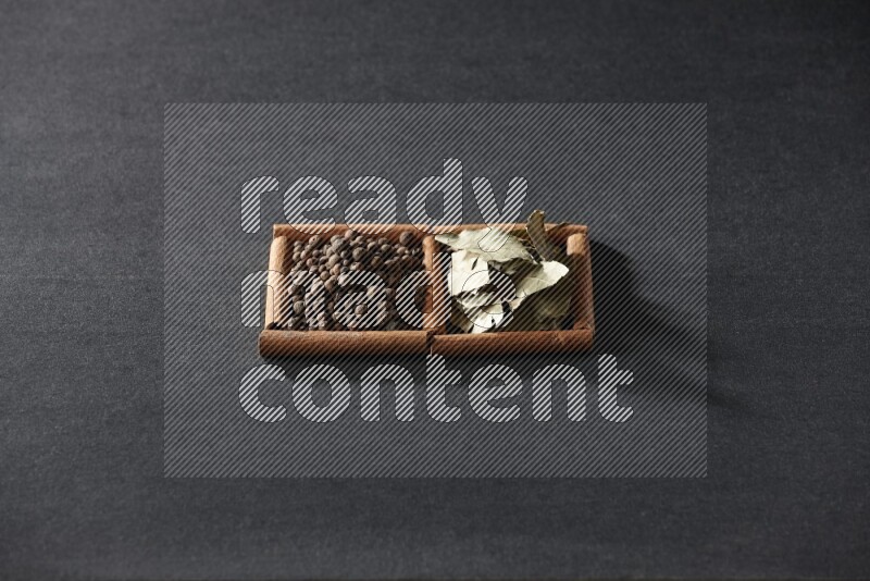 2 squares of cinnamon sticks full of allspice and bay laurel leaves on black flooring