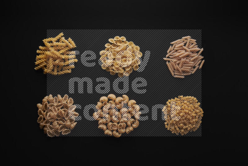 Different pasta types in bunches on black background