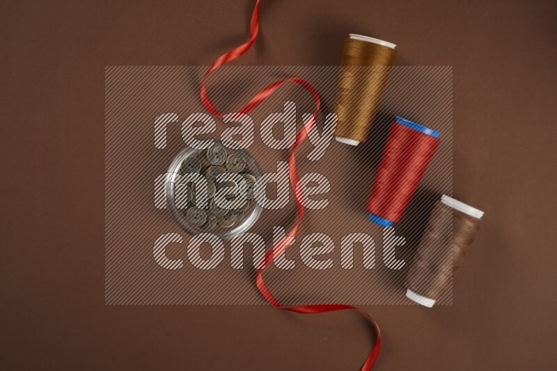 A red collection of sewing and tailoring tools arranged on a brown background