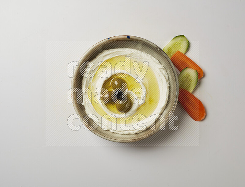 Lebnah garnished with whole olives in a grey pottery plate on a white background