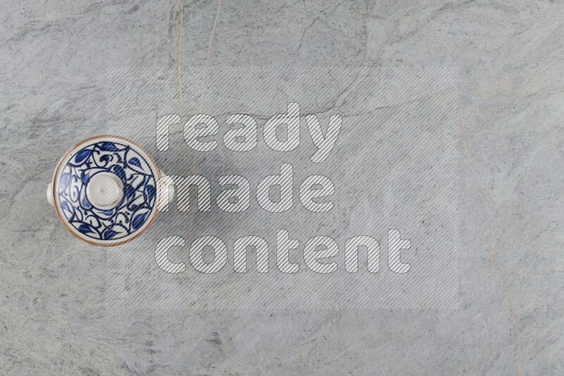 إناء فخاري متعدد الألوان مع غطائه على خلفية من الرخام الرمادي