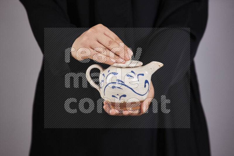A woman in black abaya holding different pottery essentials in different positions