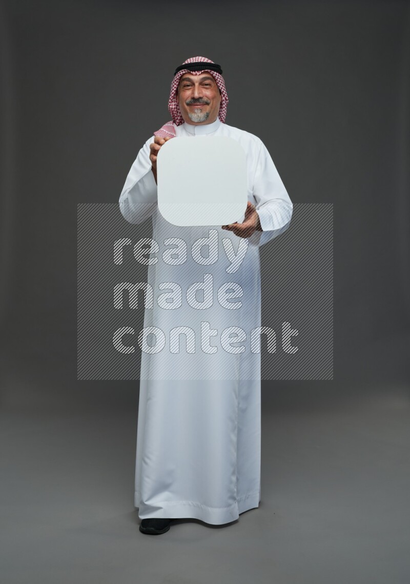 Saudi man with shomag Standing holding social media sing on gray background