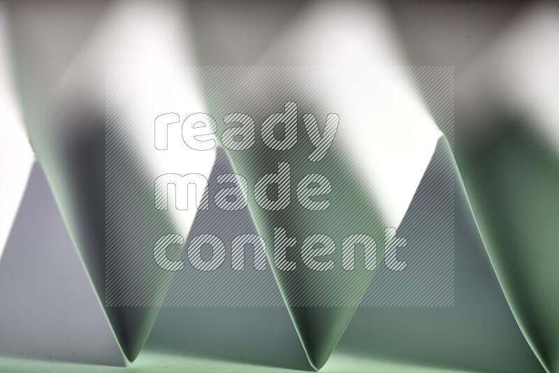 A close-up abstract image showing sharp geometric paper folds in white and green gradients
