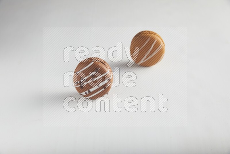 45º Shot of of two assorted Brown Irish Cream, and Brown white Chocolate Caramel macarons on white background