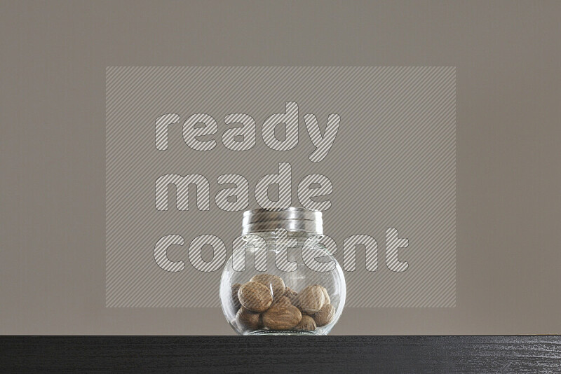 Nutmeg in a glass jar on black background