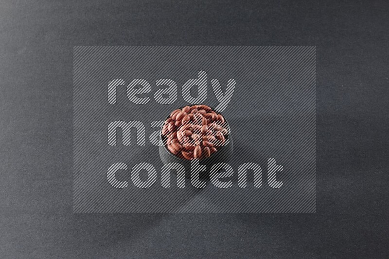 وعاء فخاري أسود ممتلئ بالفول السوداني على خلفية سوداء